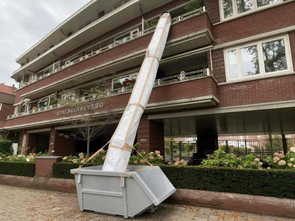 PP rubble chute hung from an upper level and running down to the skip standing on the ground below