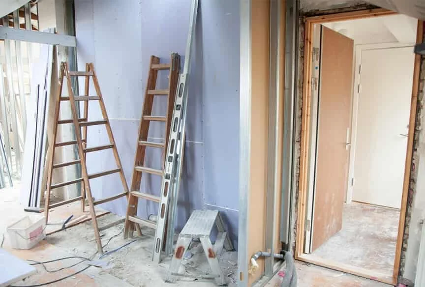 PP rubble chute hung from a renovation property into the container below, carrying strip-out rubble so the dust stays out of the stairwell