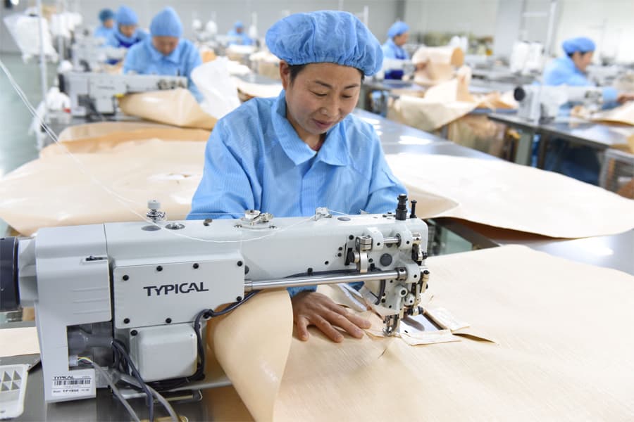 A worker sewing an FIBC bulk bag on an industrial sewing machine