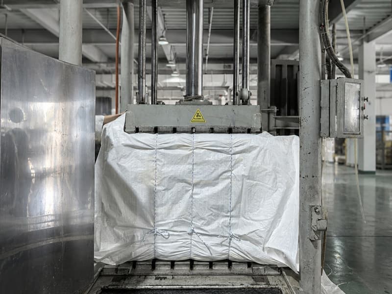 FIBC bulk bags pressed into a strapped, waterproof-wrapped hydraulic bale for export